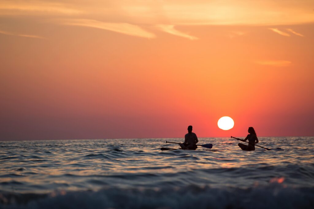 A man and women boating in the sea during the sunset