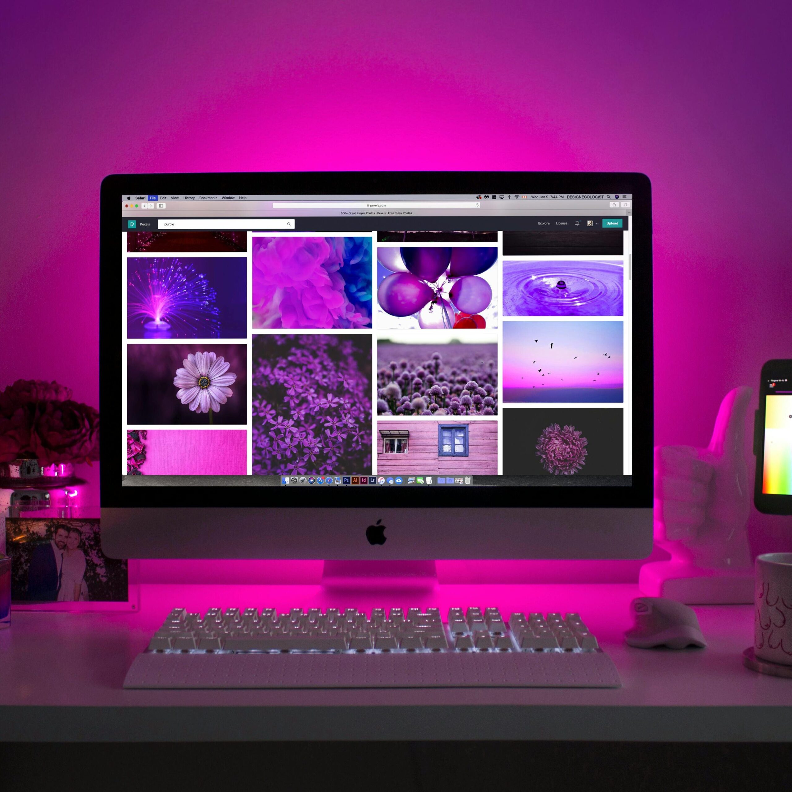 A desktop is on the table and from the background pink light is coming